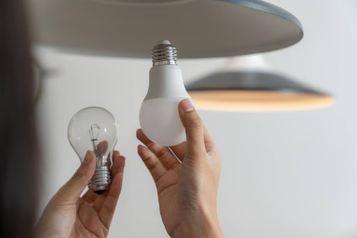 Person replacing an incandescent bulb with an LED bulb